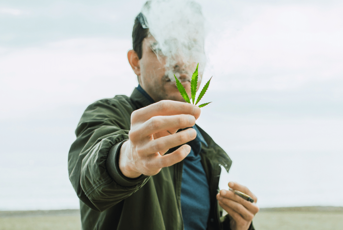 muž drží list marihuany na pláži
