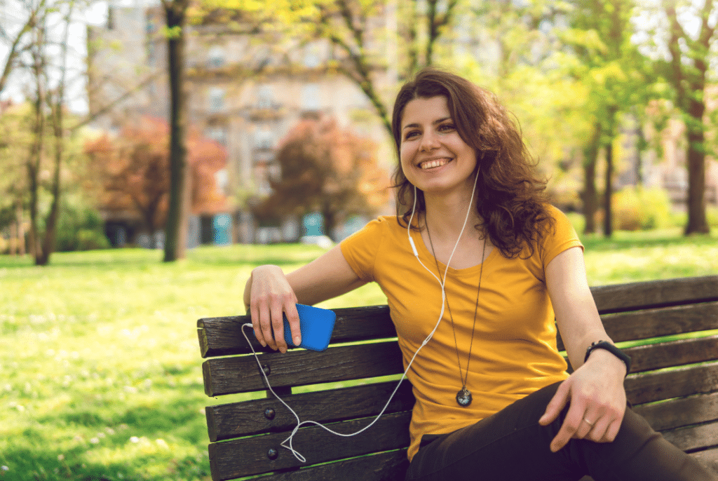 žena sedící v parku na lavičce s úsměvem