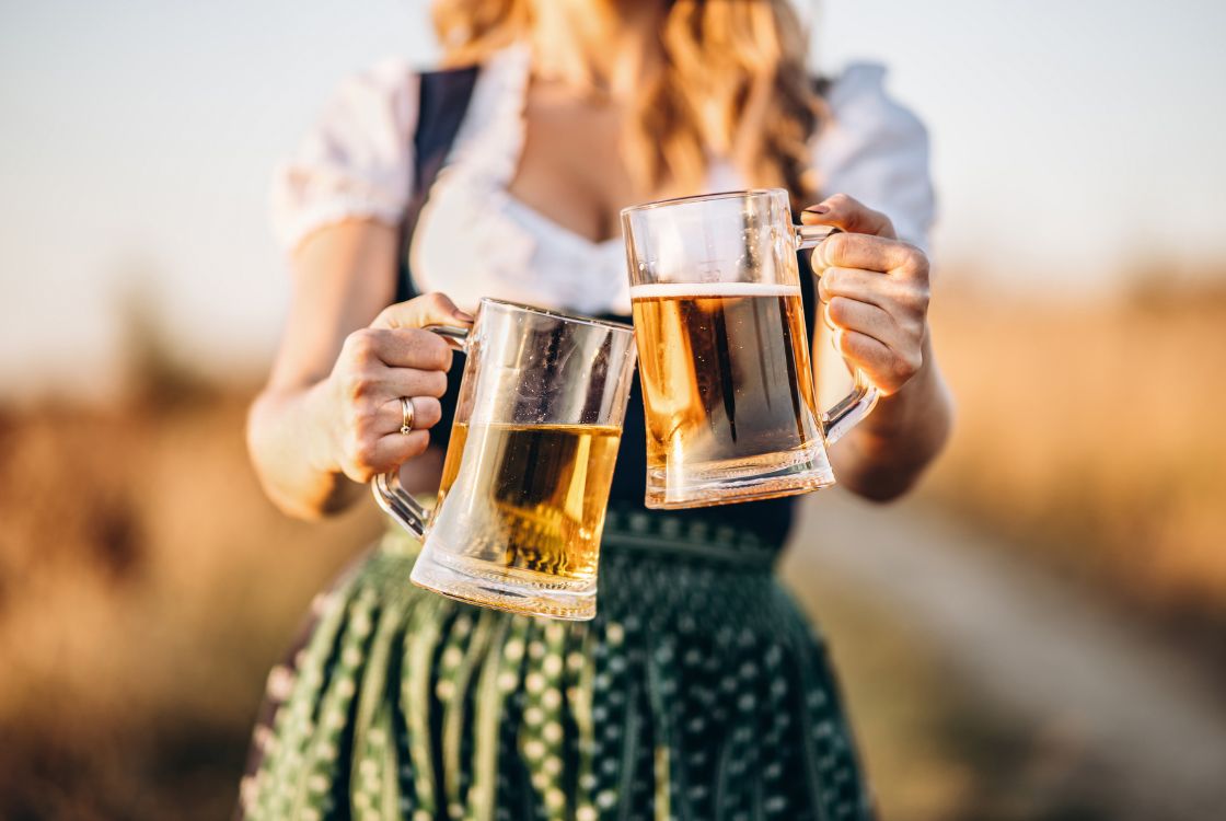žena v kroji před sebou drží piva ve sklenici