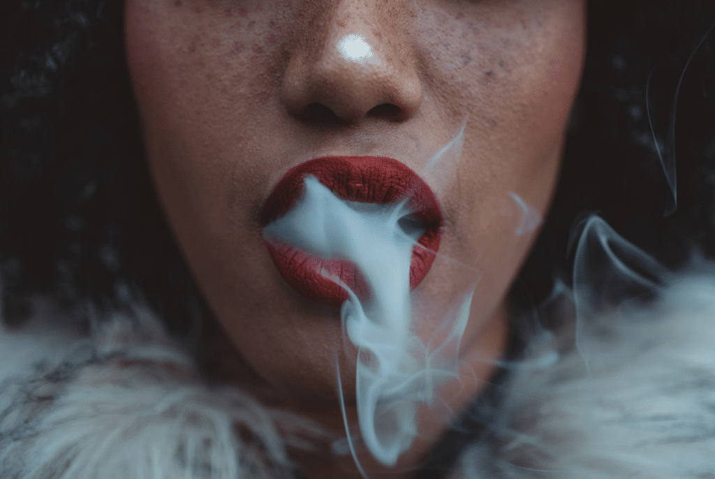 žena vydechující kouř z vaše penu