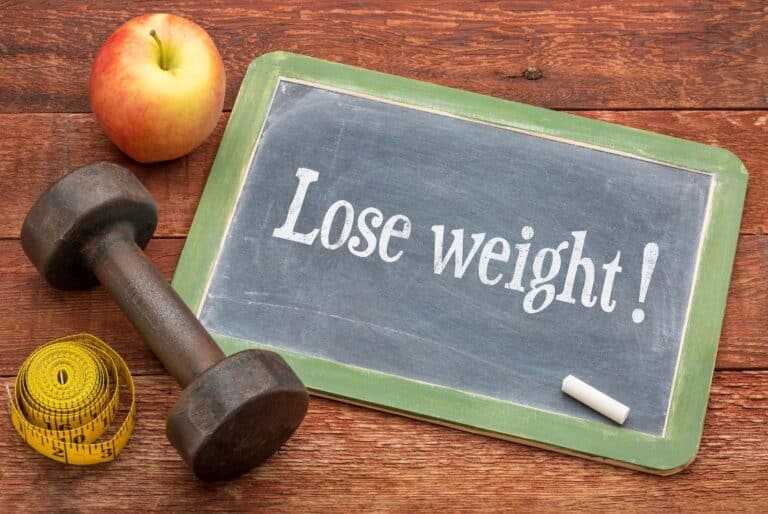 tabulka s nápisem Lose Weight, činka a jablko