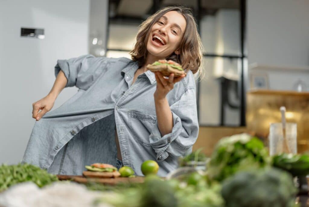 šťastná žena v košili a s jídlem v ruce